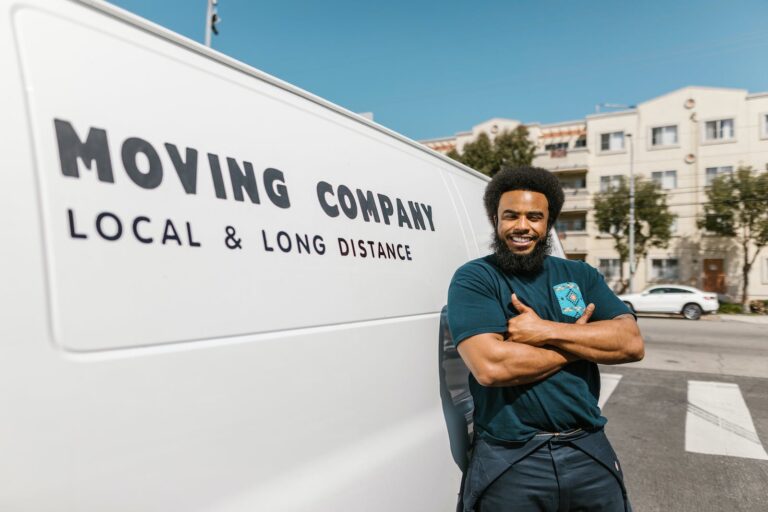 Man in Blue T-shirt and Black Pants Standing Beside White Van